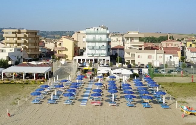 Vista dall'alto di hotel fronte mare e ombrelloni blu.