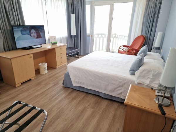 Camera con letto matrimoniale, TV e poltrona.