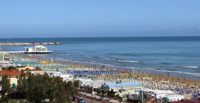 Spiaggia con file di ombrelloni colorati.