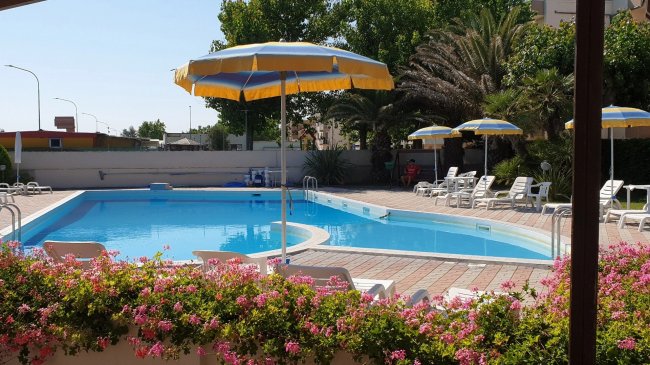 Piscina all'aperto con lettini e ombrelloni.