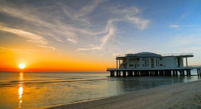 Alba sul mare con edificio su piloni.