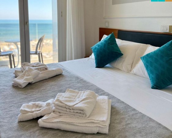 Camera da letto con vista mare e asciugamani piegati.