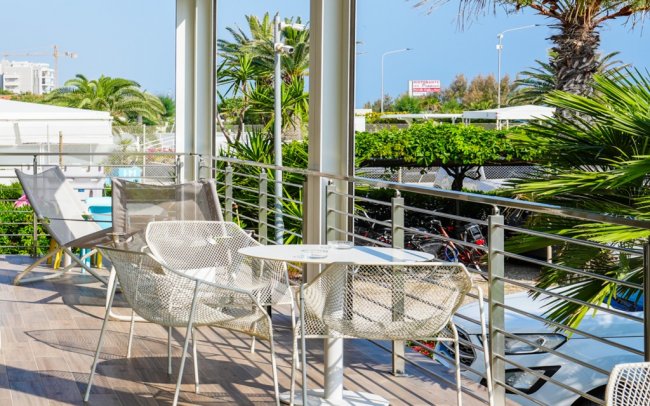 Terrazza con sedie bianche e tavolino, vista giardino.