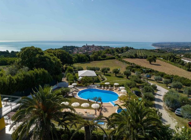 Piscina circondata da palme e veduta sul mare.