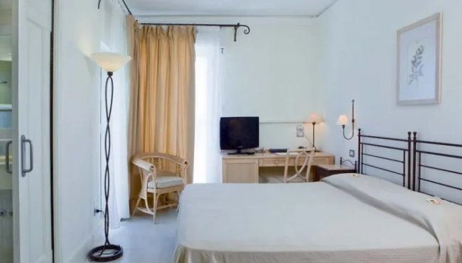 Camera con letto, scrivania, TV e poltrona.