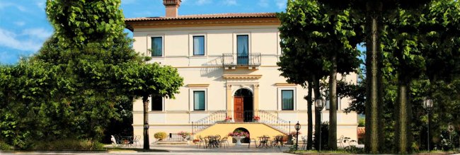 Villa bianca con giardino e alberi.