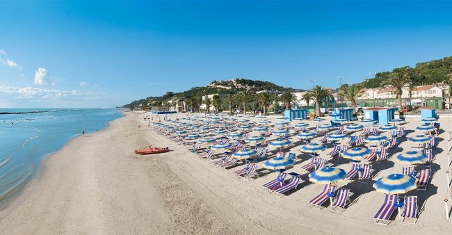 Spiaggia ampia con ombrelloni e lettini colorati.