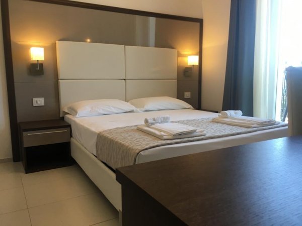 Camera d'hotel con letto matrimoniale e lampade accese.