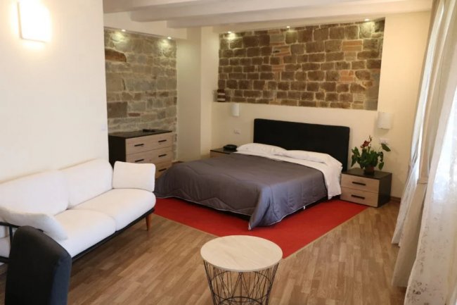 Camera con letto, divano bianco e parete in pietra.