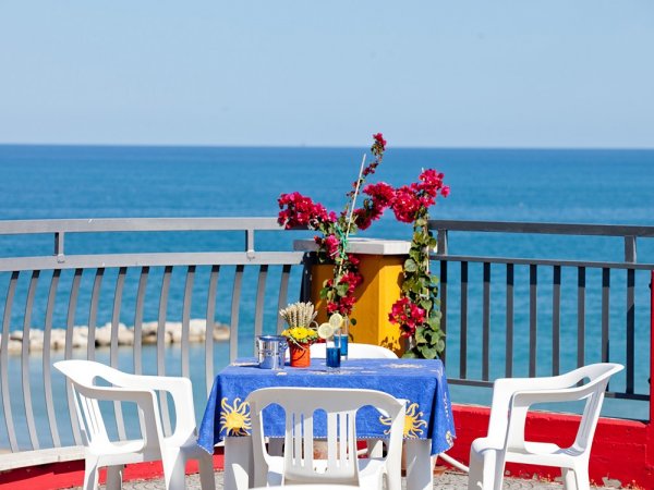 Tavolo con sedie vista mare e fiori.