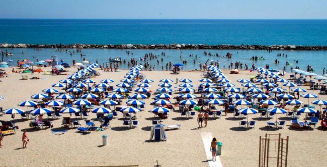 Spiaggia con ombrelloni blu e bianchi.