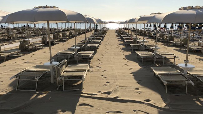 Spiaggia con lettini e ombrelloni allineati.