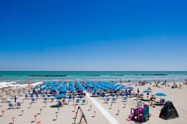 Spiaggia con ombrelloni blu e giochi per bambini.