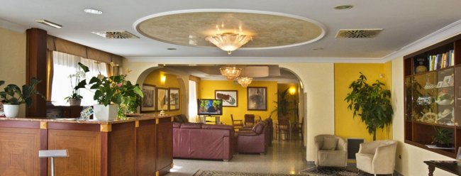 Sala d'attesa con poltrone, piante e illuminazione soffusa.