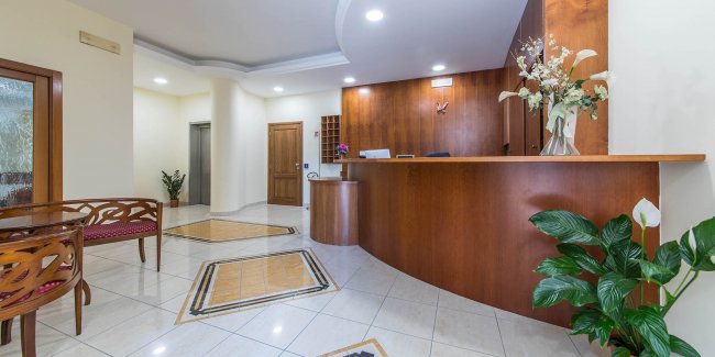 Reception elegante con bancone in legno e piante decorative.