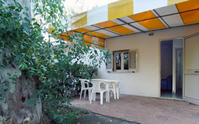 Patio con sedie bianche e tettoia gialla.