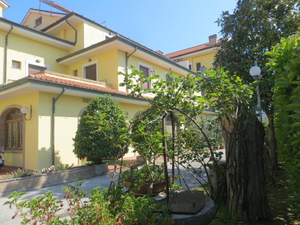 Esterno di un edificio giallo con giardino.