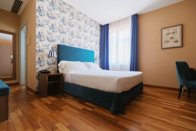 Camera da letto con carta da parati blu e letto matrimoniale.