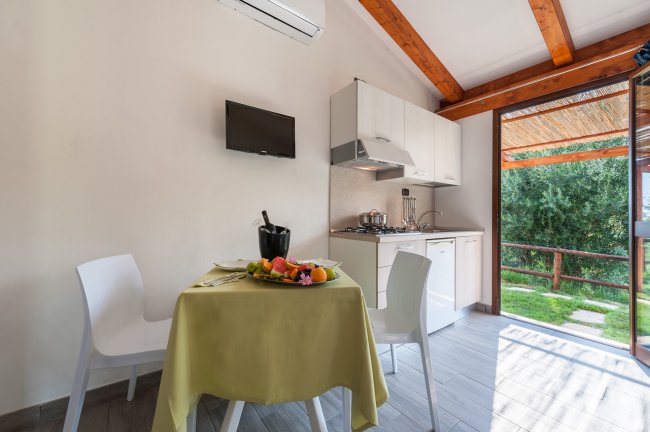 Cucina con tavolo apparecchiato e vista sul giardino.