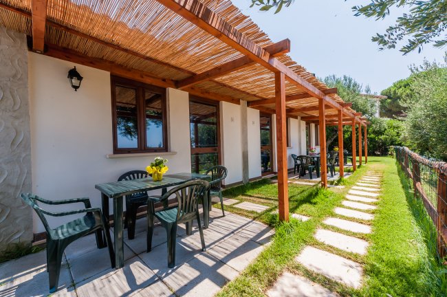 Terrazza con tavoli e sedie sotto pergolato di legno.