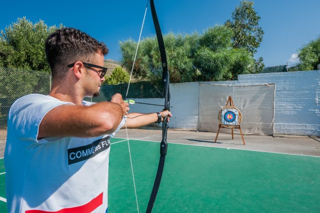 Uomo che pratica tiro con l'arco su un campo all'aperto.