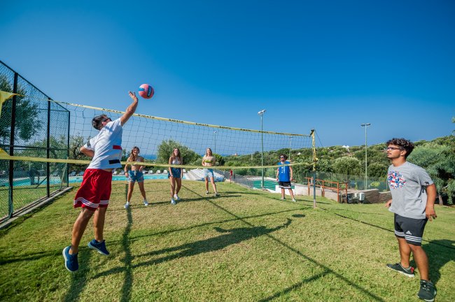Gruppo di persone gioca a pallavolo su un campo erboso.