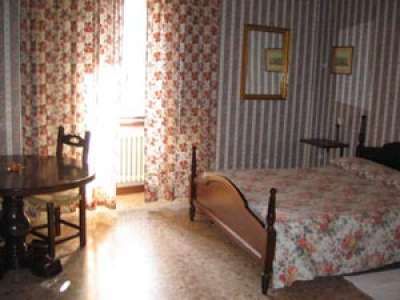 Una camera con letto matrimoniale, tende a fiori e pareti a righe.