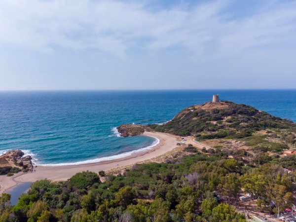 Spiaggia e promontorio con torre vicino al mare.
