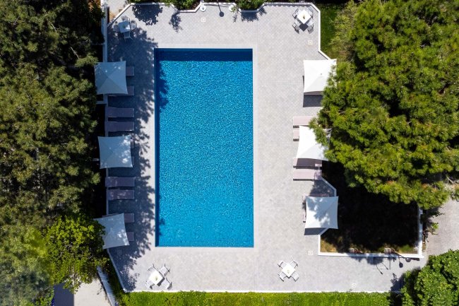 Piscina rettangolare circondata da lettini e ombrelloni.