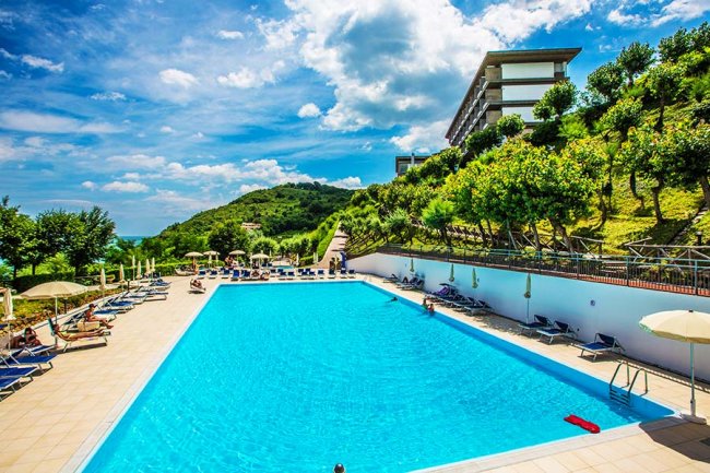 Piscina all'aperto con lettini e ombrelloni.