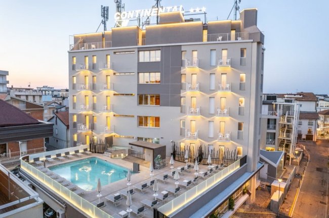 Edificio illuminato con piscina sul tetto e scritta 