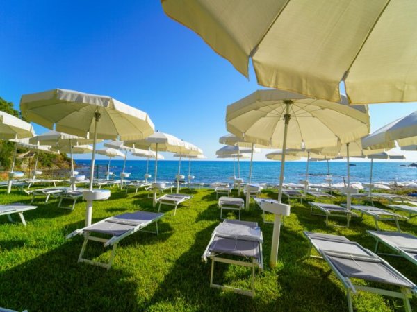 Ombrelloni e lettini su prato vicino al mare.