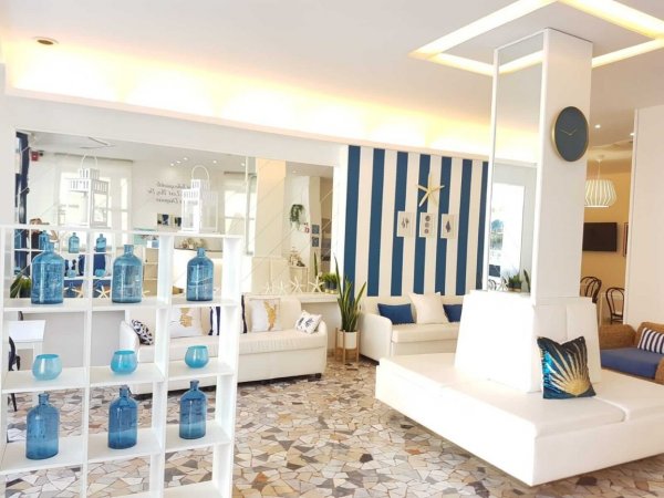 Interno luminoso di una sala con divani bianchi e dettagli blu.