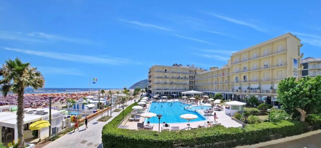 Piscina all'aperto con ombrelloni vicino al mare.