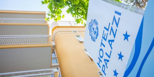 Insegna blu di un hotel vicino a un edificio arancione con balconi.