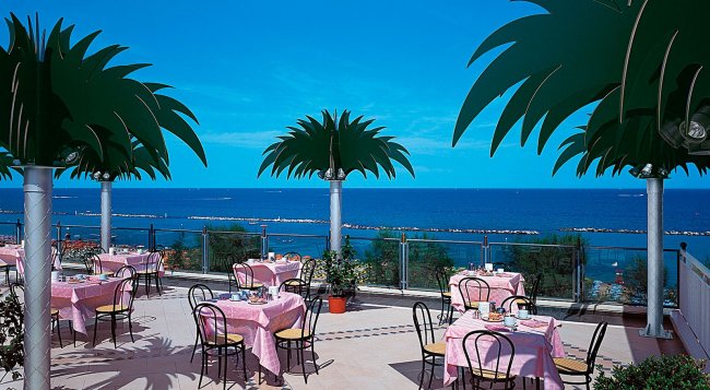 Ristorante all'aperto vista mare, tavoli con tovaglie rosa.