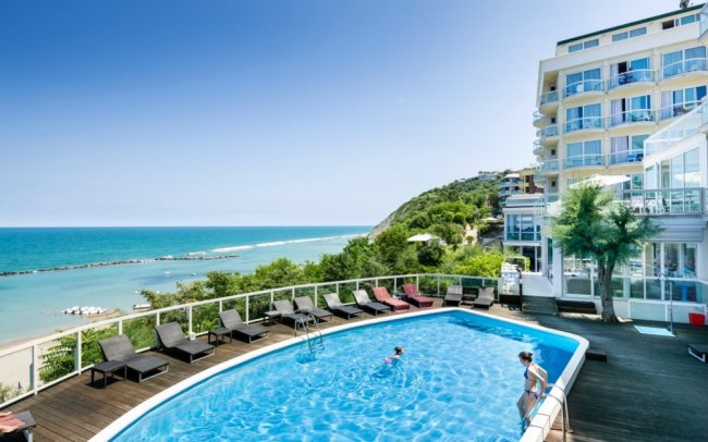 Piscina con vista mare e lettini.