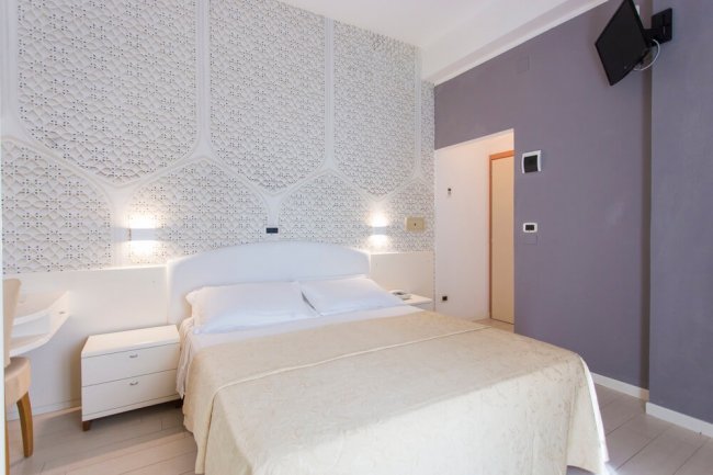 Camera da letto moderna con arredi chiari e decorazioni a parete.