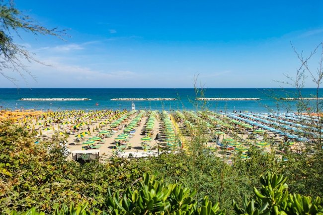 Spiaggia con ombrelloni colorati e mare azzurro.