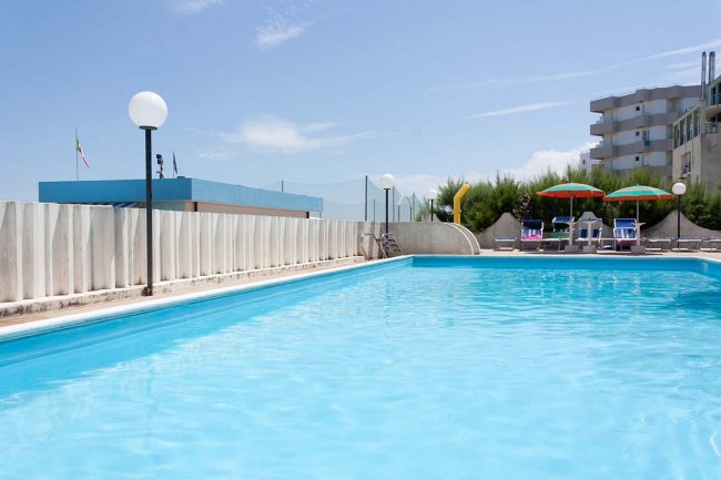 Piscina all'aperto con cielo sereno e ombrelloni.