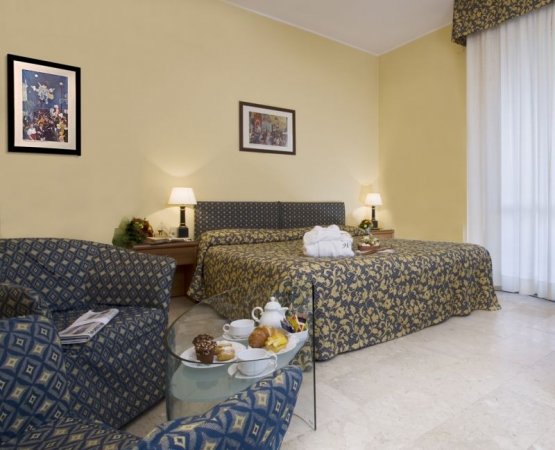 Camera d'albergo con letto matrimoniale e divano.