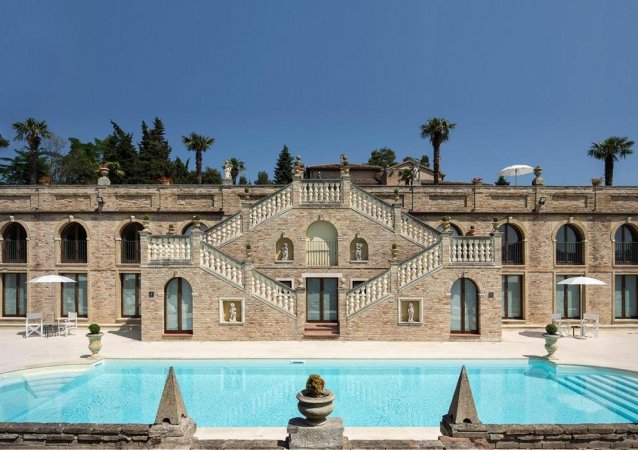 Un'elegante villa in pietra con piscina, scale e statue.