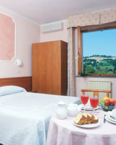 Una camera da letto con letto matrimoniale, tavolino con colazione e vista su colline.