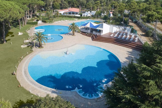 Grandi piscine circondate da aree verdi e sedie a sdraio.