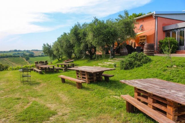 Tavoli di legno in un giardino verde vicino ad una casa.