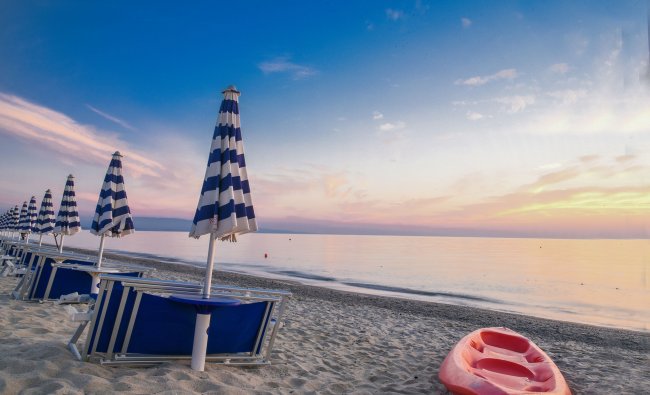 Spiaggia al tramonto con ombrelloni.