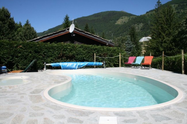 Una piscina all'aperto con lettini colorati e montagne sullo sfondo.