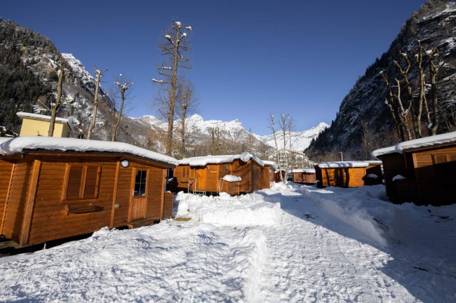 Case di legno innevate tra montagne.