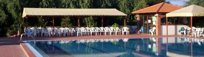 Piscina con sedie bianche e tettoie.