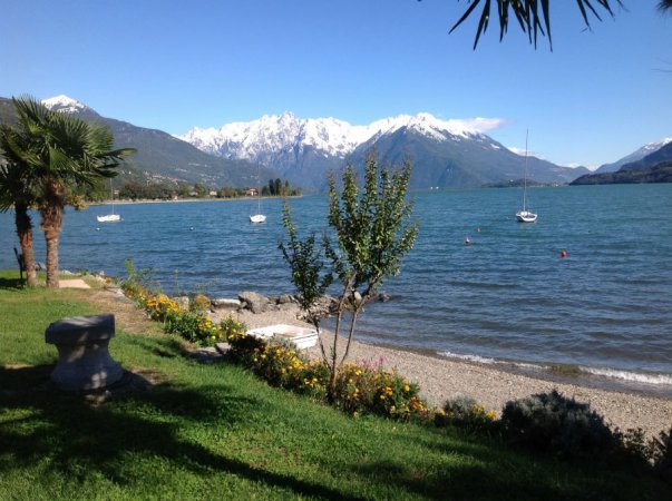 Lago con monti innevati e barche a vela.